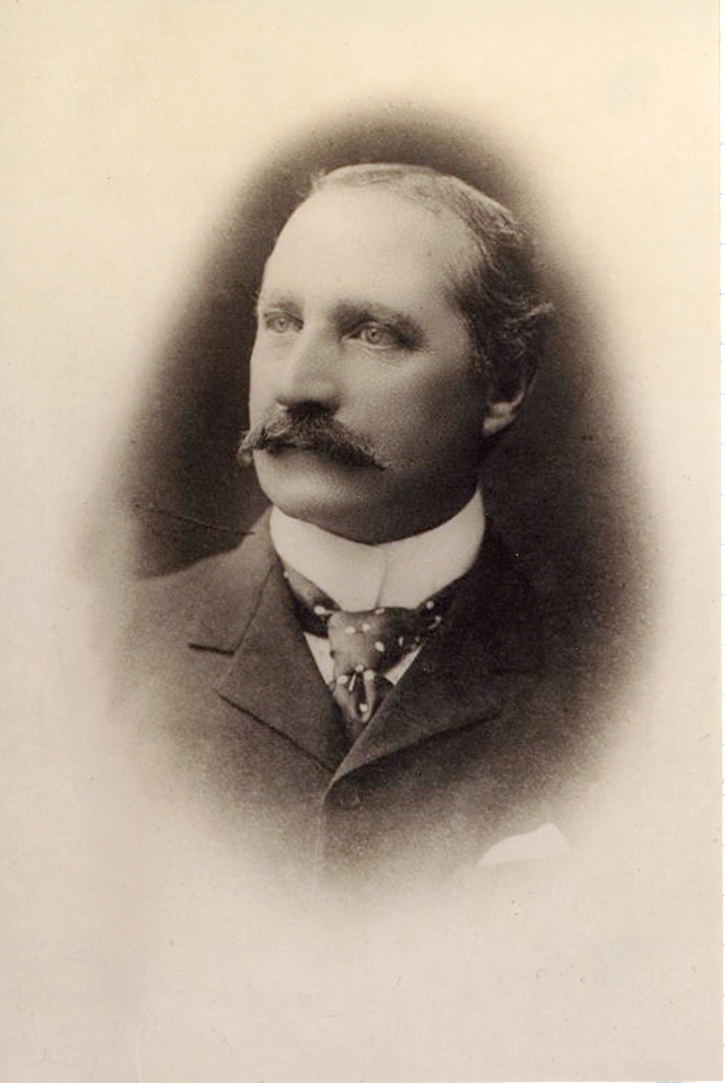 Sepia photo of man with moustache in jacket, tie and white collar