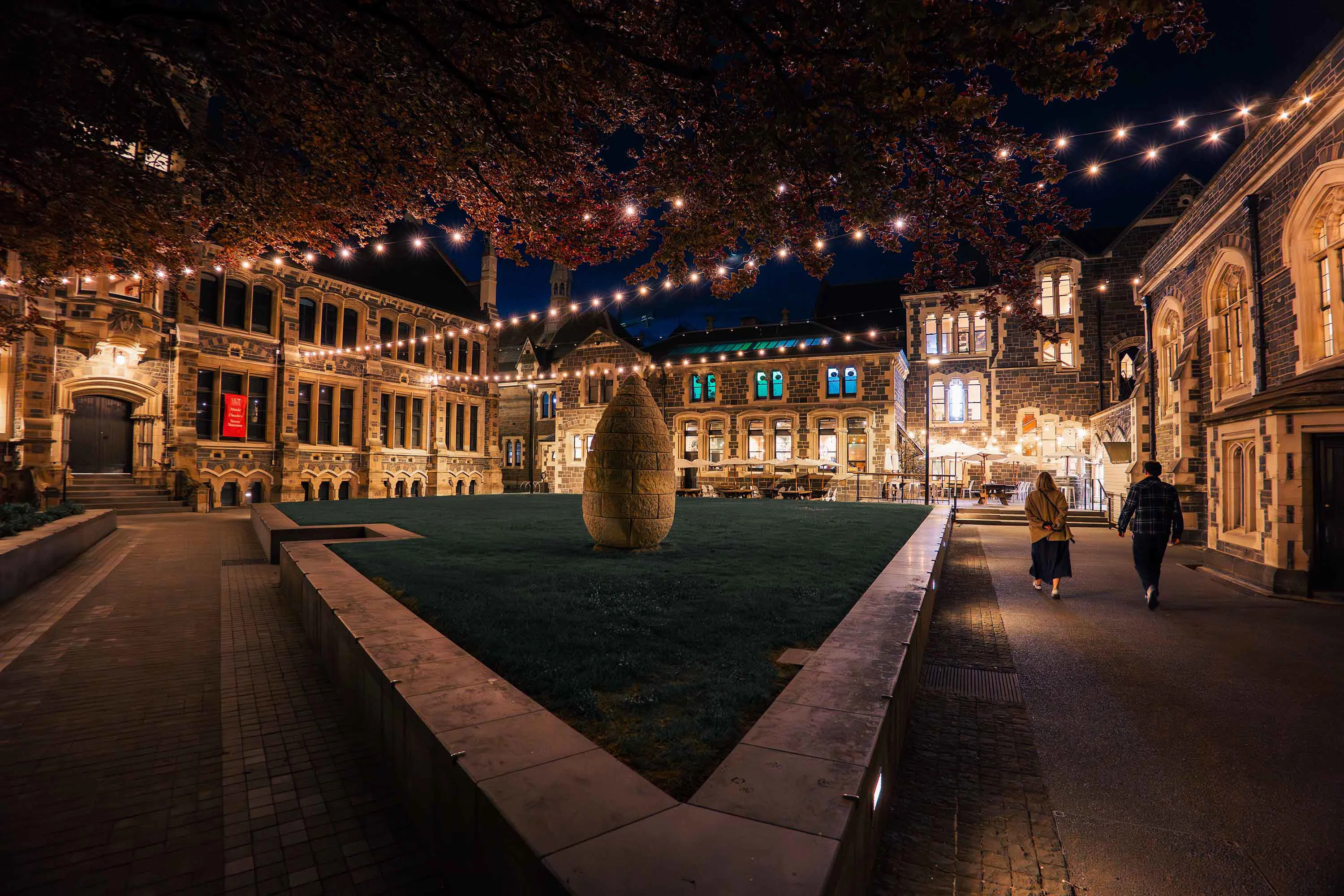 Te Matatiki Toi Ora The Arts Centre quad at night lit up with festoons, old neogothic building in the background. 