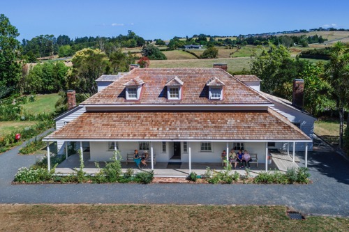 Aerial view of shingle-roofed cottage against green landscapte