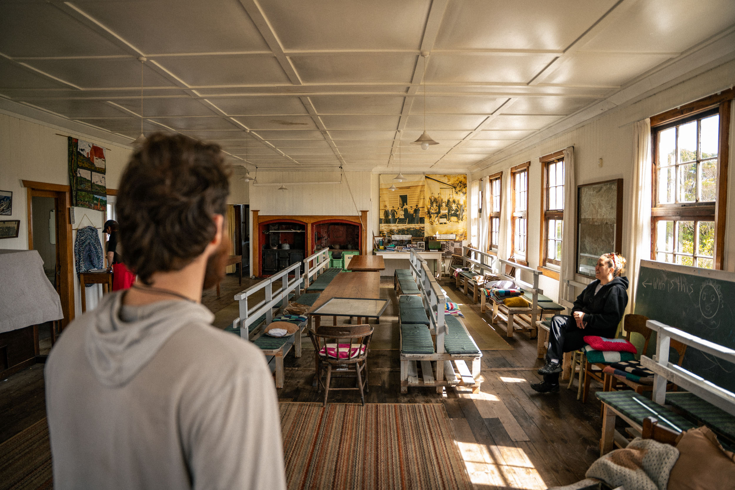 man looks into long room with school tables and old fashioned furniture