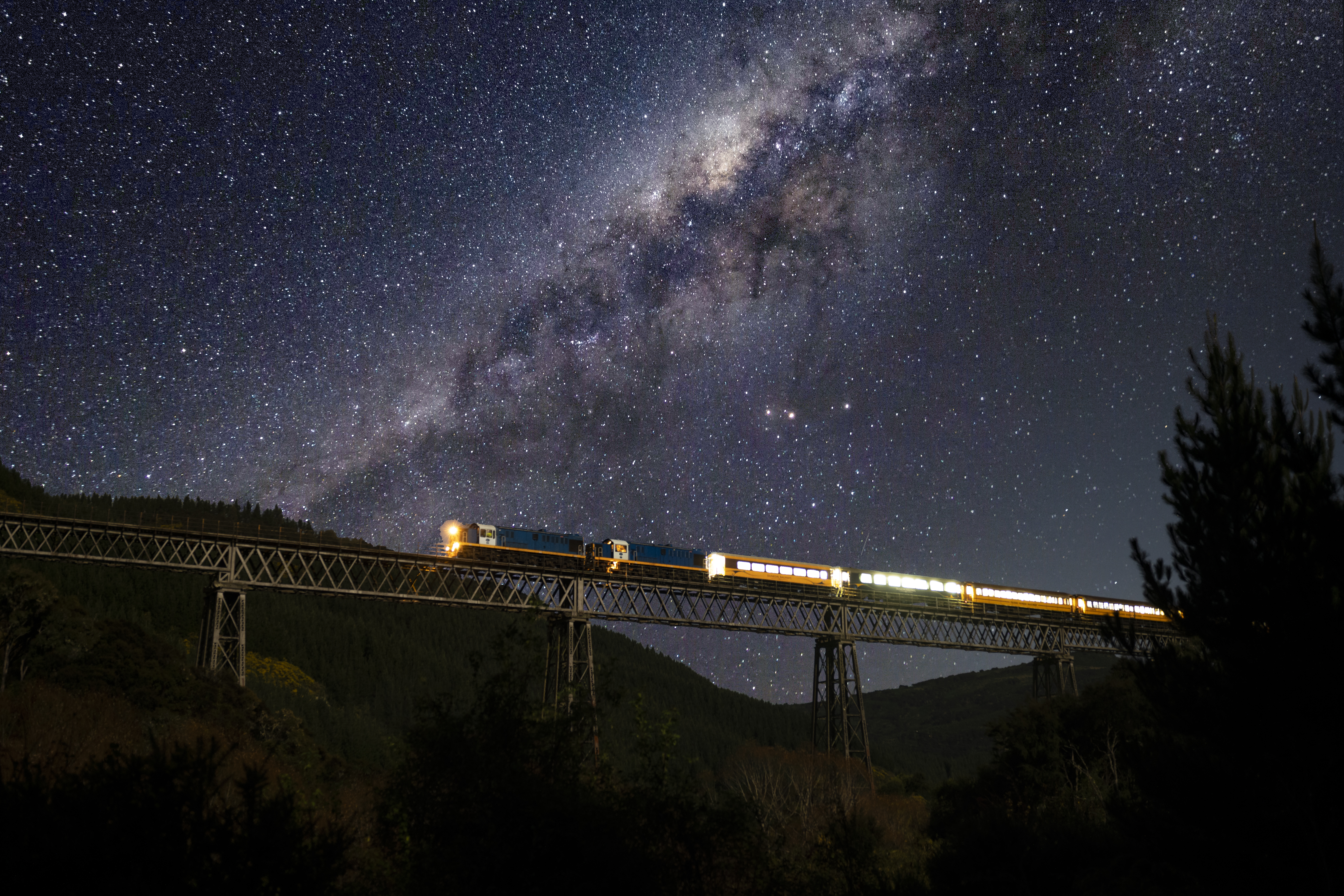 train driving at night over a bridge under the stars