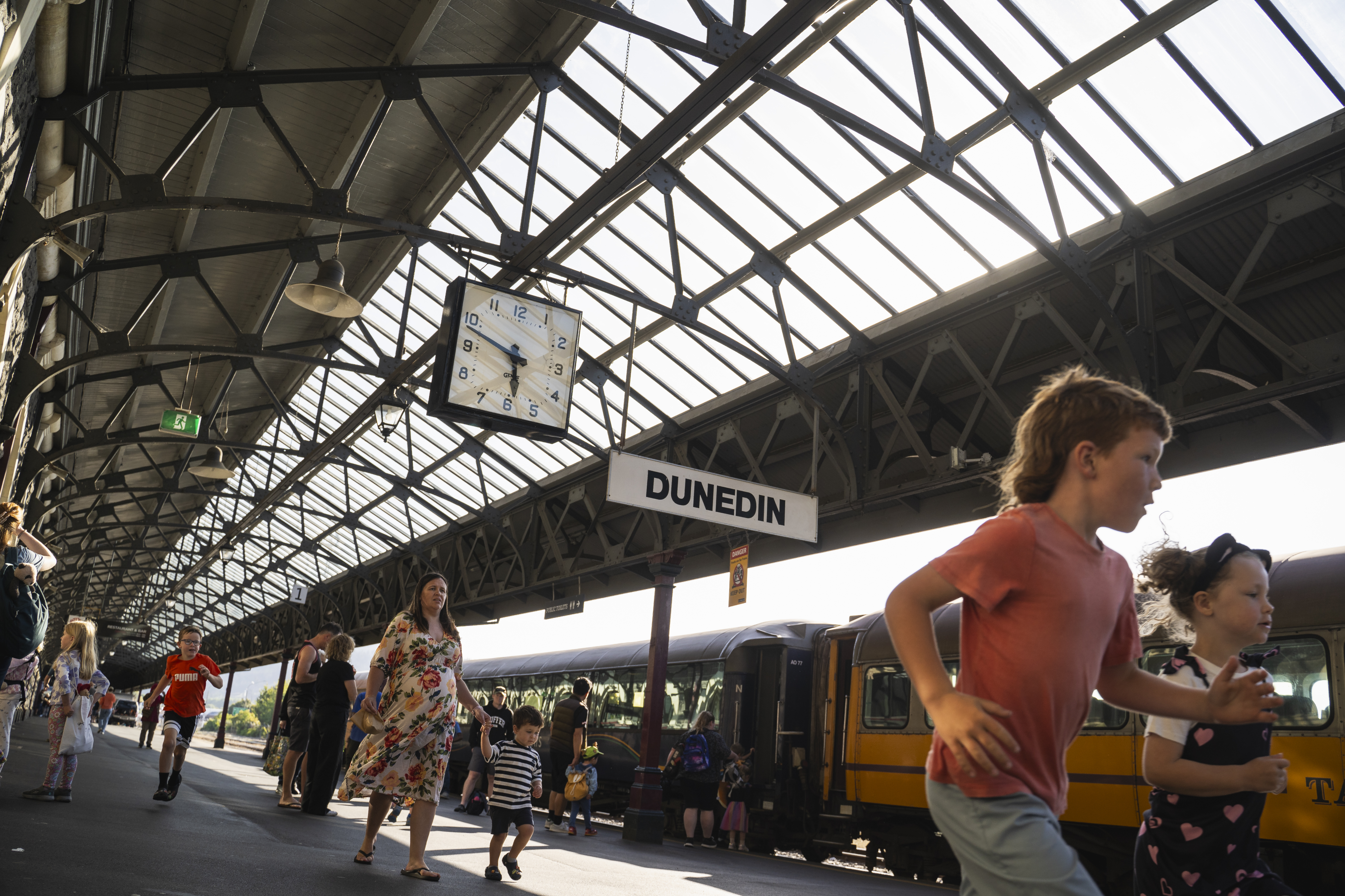 People on busy train platform, kids running in foreground.