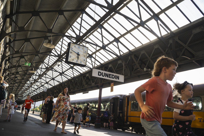 People on busy train platform, kids running in foreground.