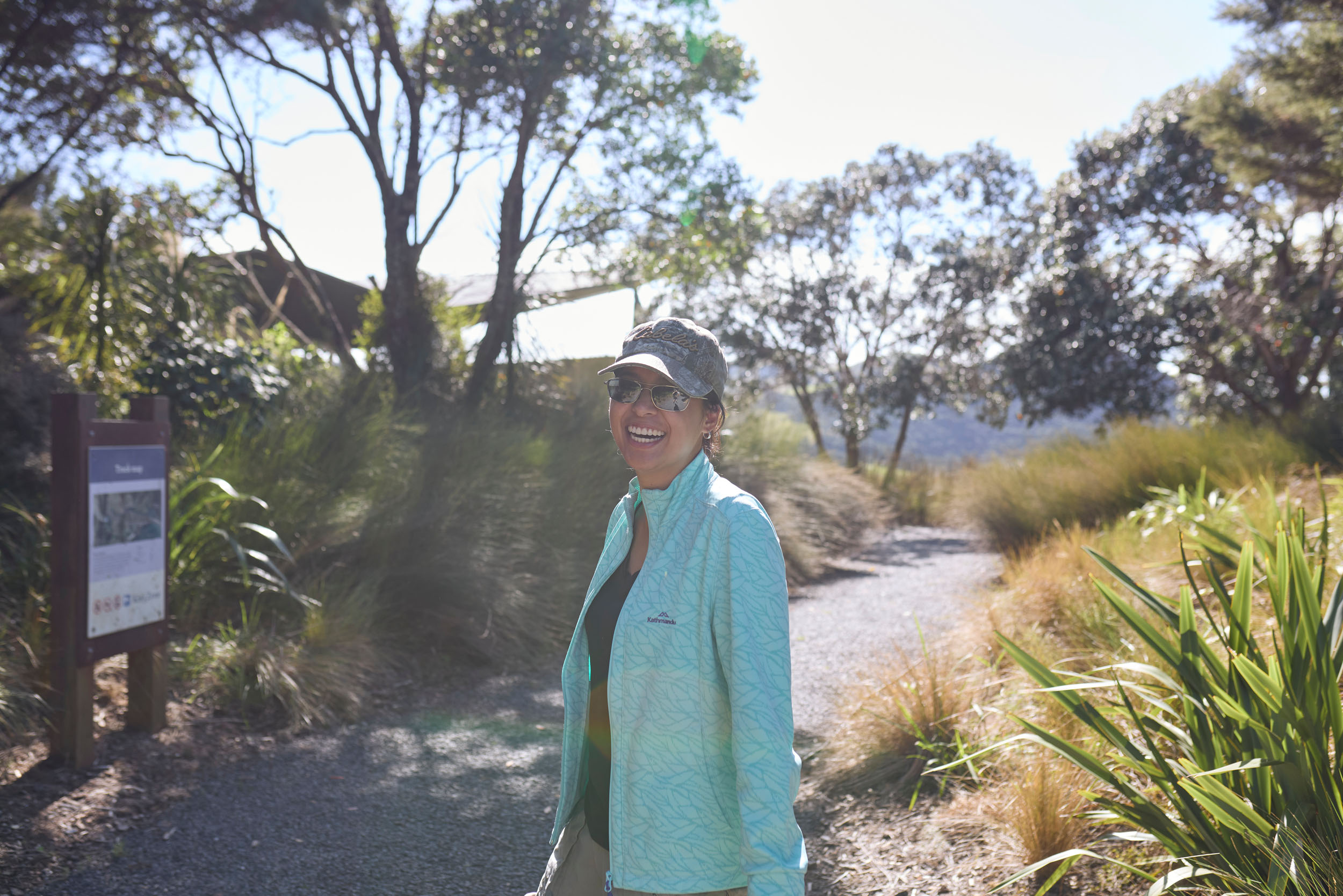young woman smiles on walkway surrounded by trees