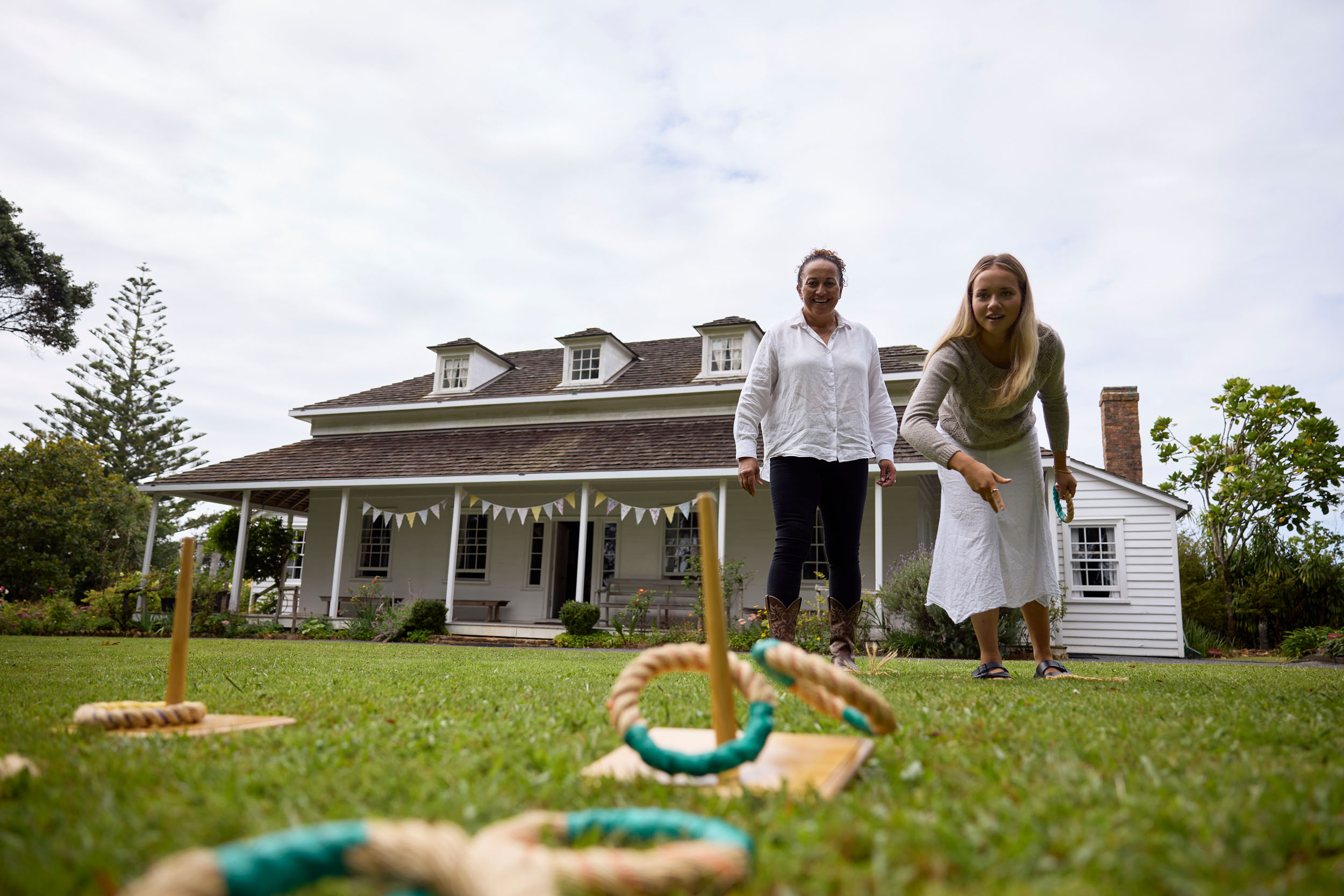 young woman and older woman throwing hoops in front of old building with verandah