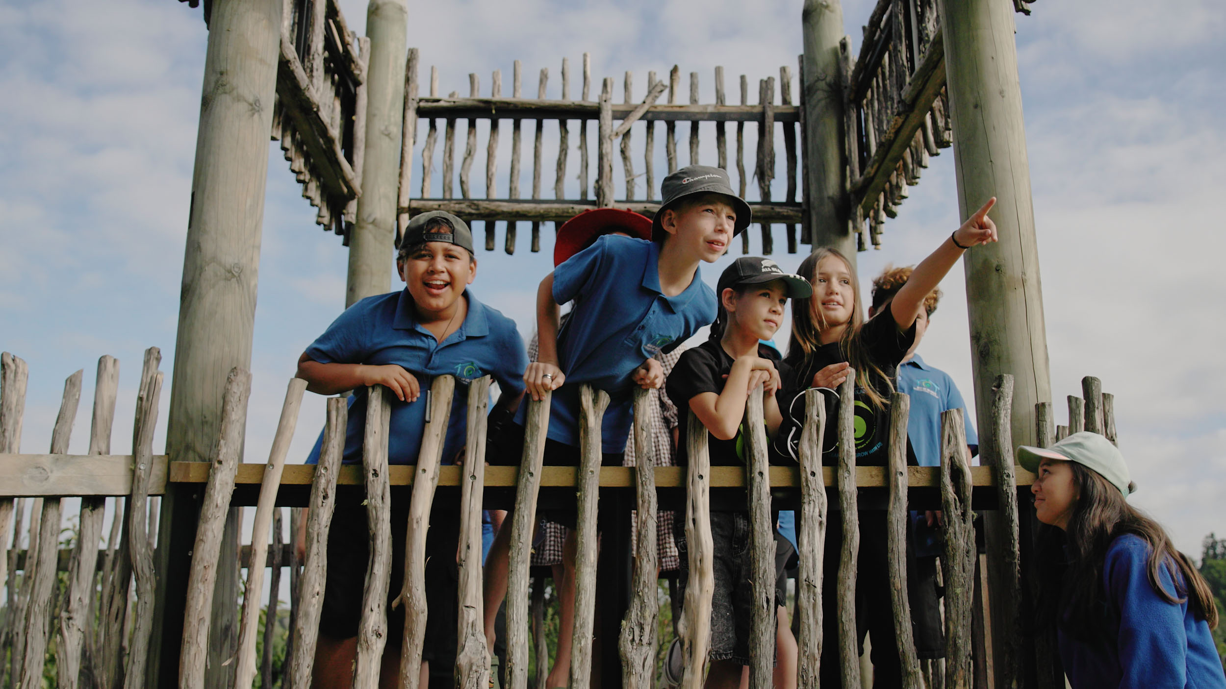 children in school uniform looking out of wooden fort