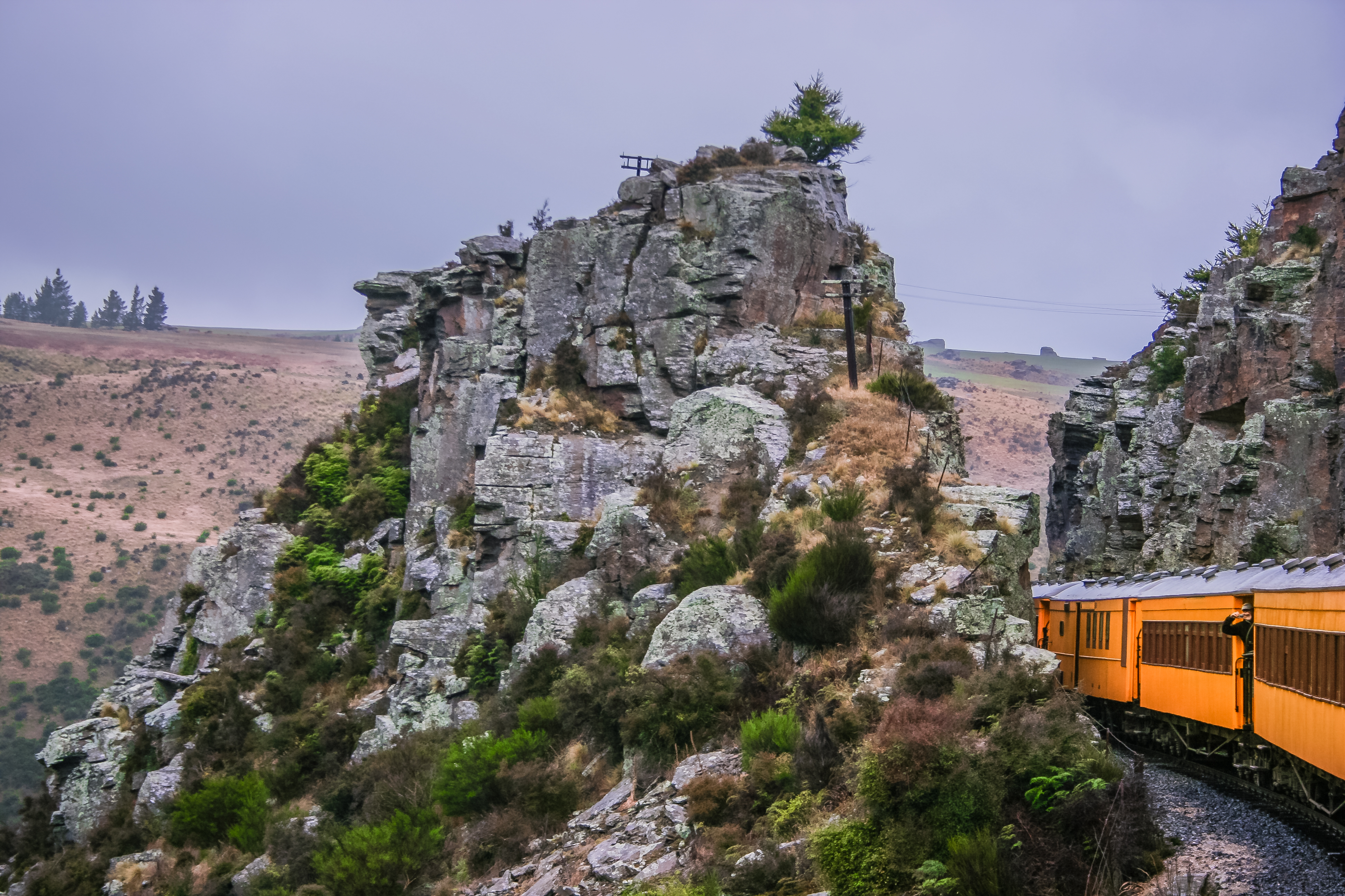 A yellow train cuts through a rocky gorge