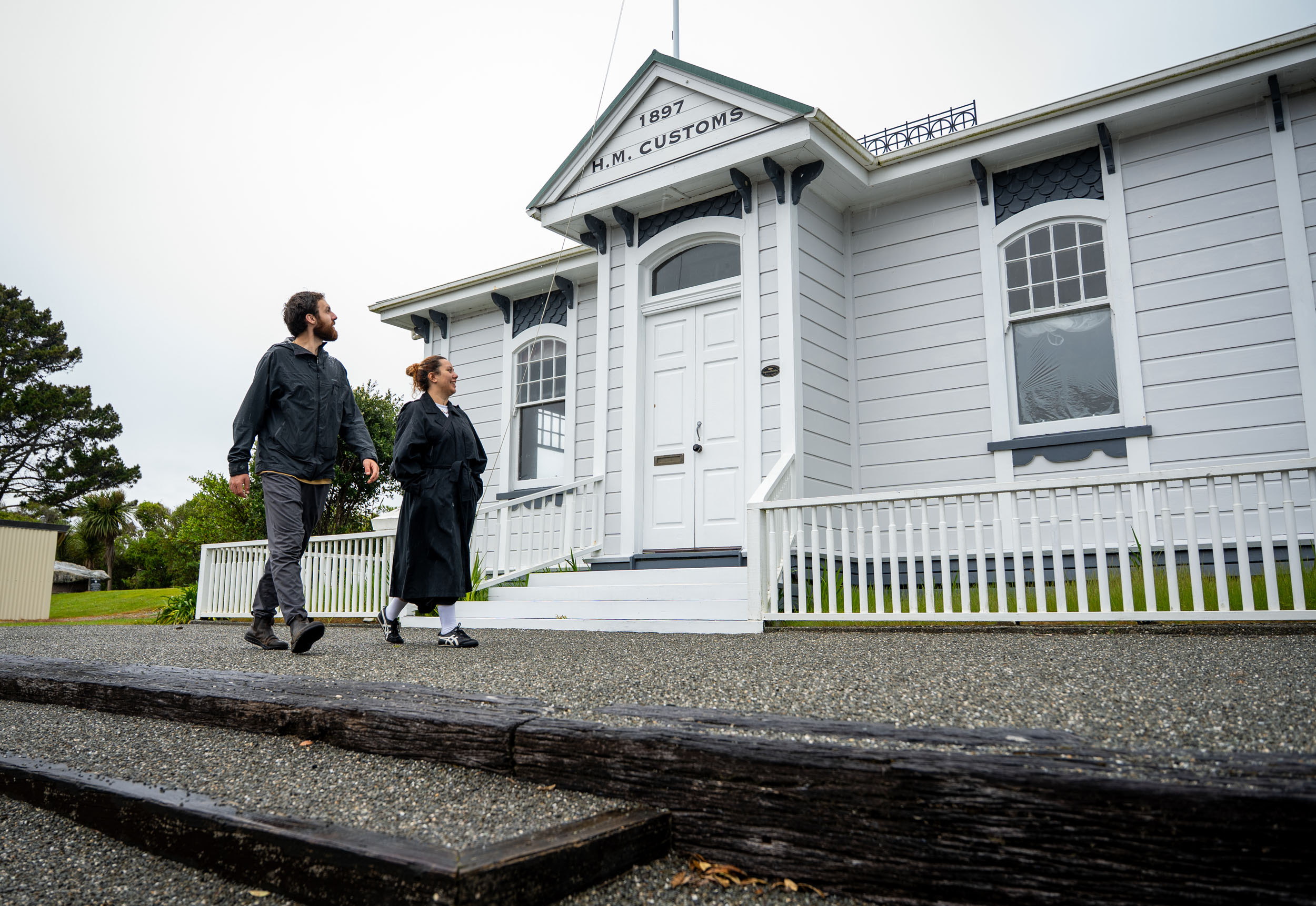 man and woman walk past white weatherboard customhouse