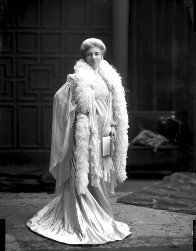 black and white photo of lady in flowing silk gown and feather boa