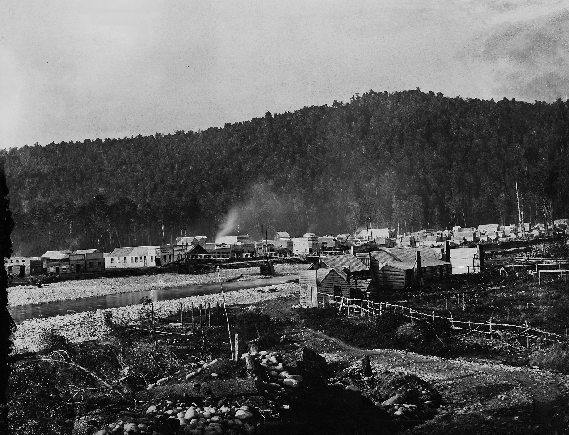 black and white photo of old town, wooded hill behind