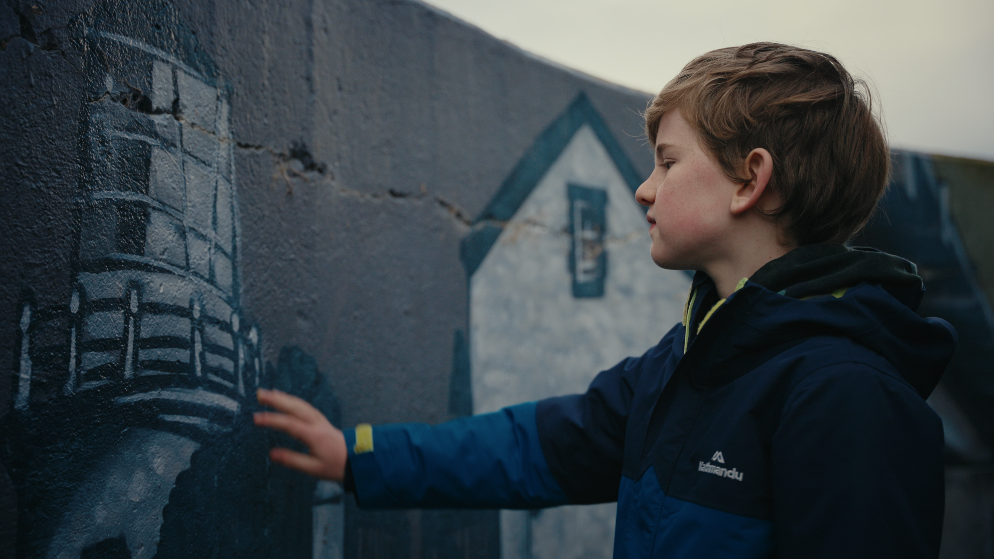 boy touches painted mural on curved wall