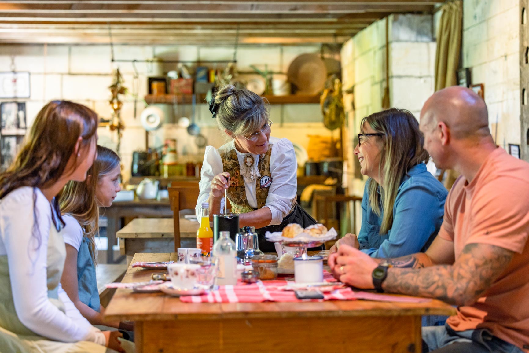 Lady serves party coffee at a table inside historic stone building