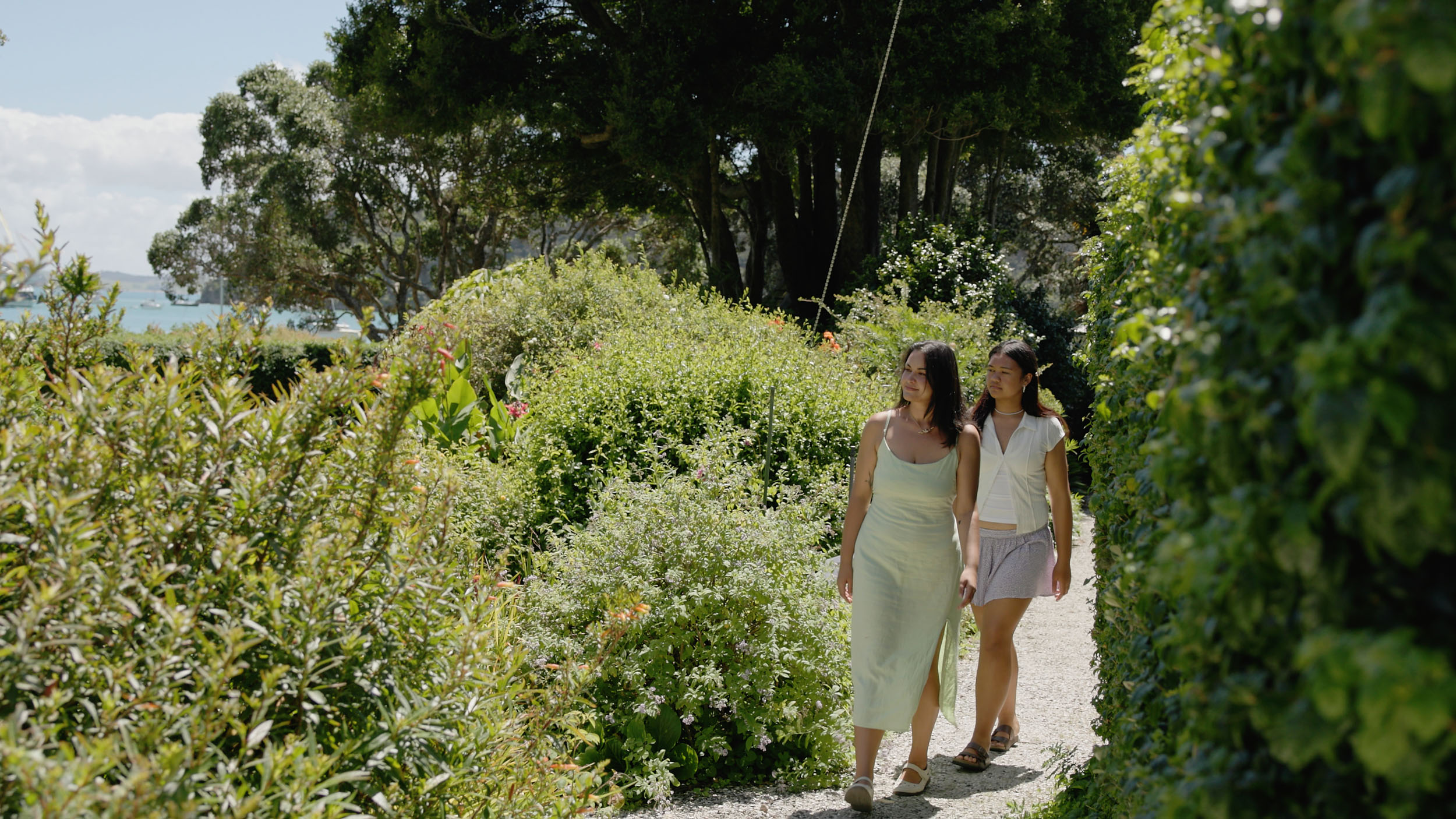 Two young women walk through cottage gardens